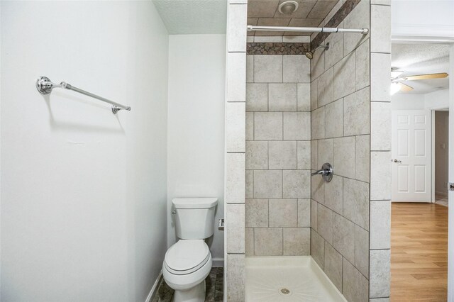 bathroom with hardwood / wood-style flooring, ceiling fan, tiled shower, a textured ceiling, and toilet