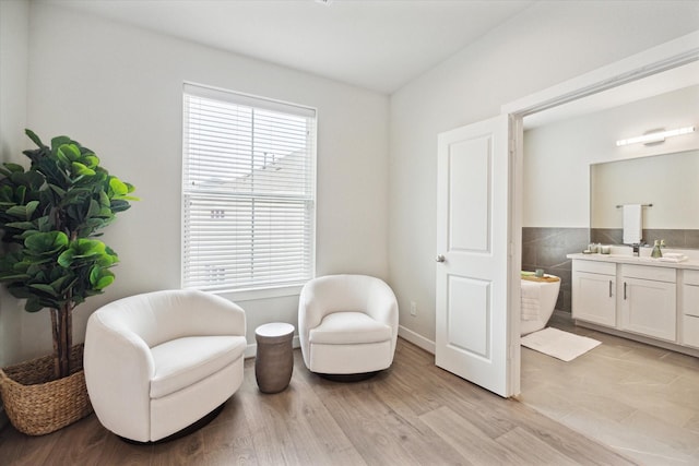 living area with sink, a wealth of natural light, and light hardwood / wood-style floors