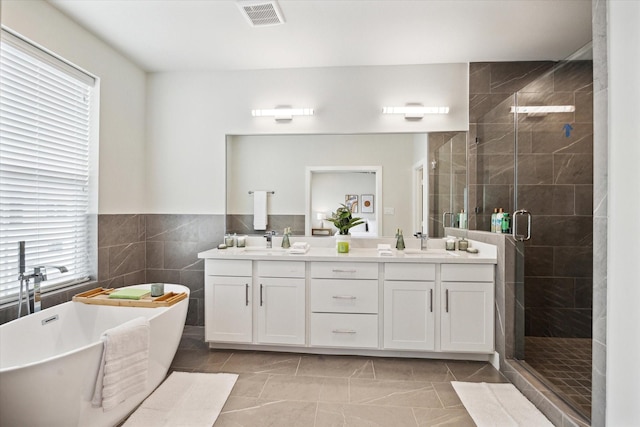 bathroom featuring vanity, plus walk in shower, and tile walls