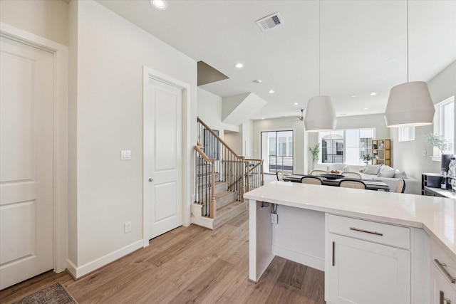 kitchen featuring visible vents, white cabinets, open floor plan, light countertops, and light wood-type flooring