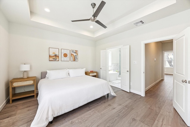 bedroom featuring visible vents, light wood finished floors, and a raised ceiling