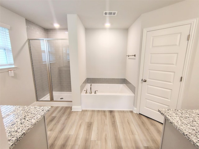 bathroom featuring wood-type flooring, separate shower and tub, and vanity