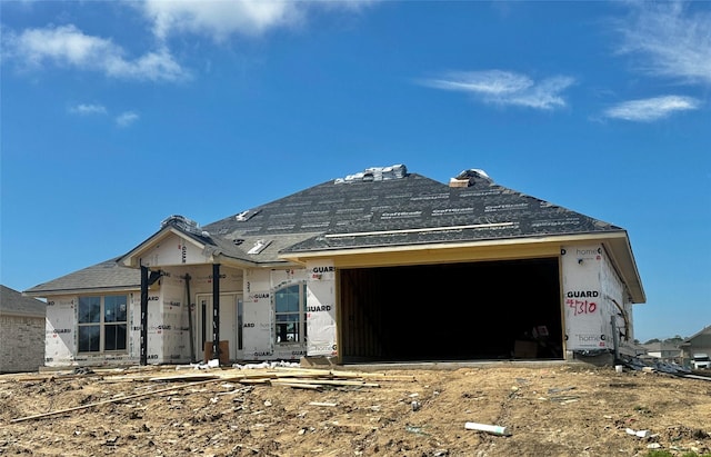 property under construction with an attached garage and roof with shingles