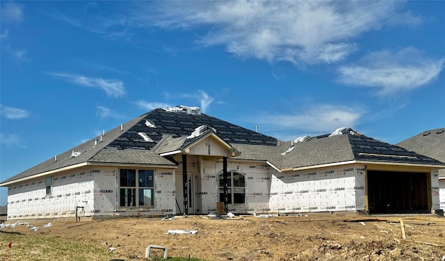 unfinished property featuring roof with shingles and an attached garage