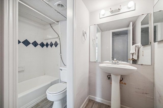 full bathroom with sink, tiled shower / bath combo, wood-type flooring, and toilet