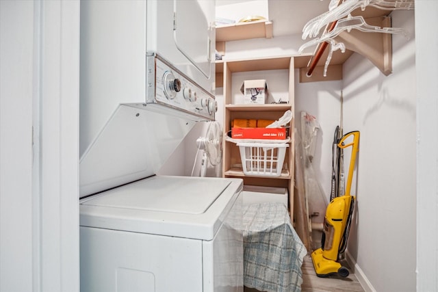 laundry area with hardwood / wood-style floors and stacked washer / dryer