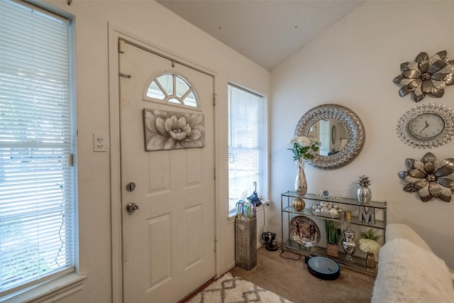 carpeted entrance foyer with vaulted ceiling