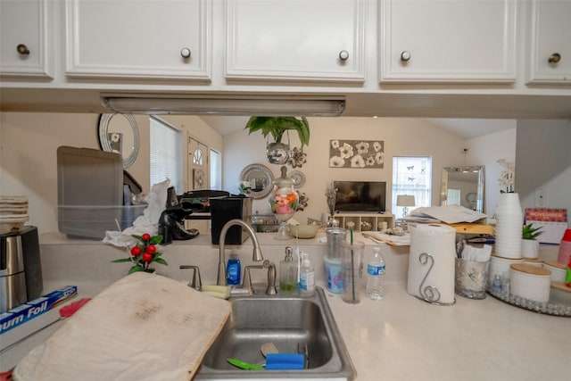 kitchen with white cabinetry, vaulted ceiling, and sink