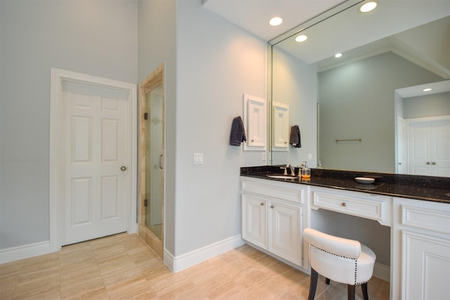 bathroom featuring a shower with door, vanity, and vaulted ceiling