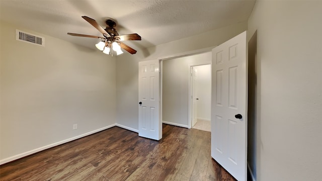 unfurnished bedroom with dark wood-type flooring, ceiling fan, and a textured ceiling