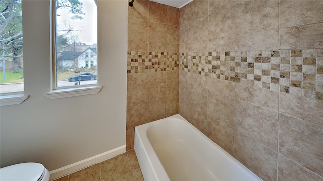 bathroom featuring tile patterned floors, toilet, and tiled shower / bath combo