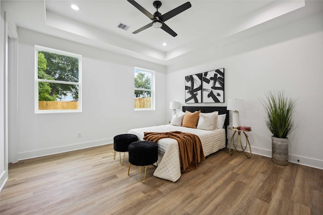 bedroom featuring hardwood / wood-style floors, a tray ceiling, and ceiling fan