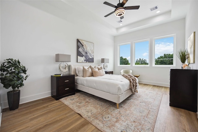 bedroom featuring ceiling fan, a tray ceiling, and hardwood / wood-style floors