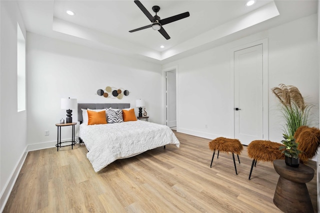 bedroom featuring a raised ceiling, ceiling fan, and light hardwood / wood-style floors