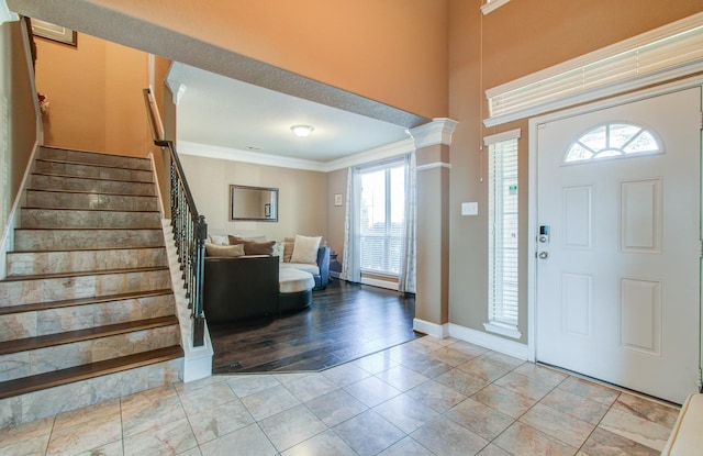 foyer entrance featuring light tile patterned floors, ornamental molding, and ornate columns