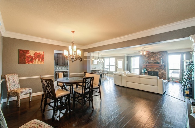 dining room with crown molding, dark hardwood / wood-style floors, ceiling fan with notable chandelier, and a fireplace