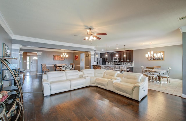 living room with ceiling fan with notable chandelier, ornamental molding, dark hardwood / wood-style floors, and decorative columns