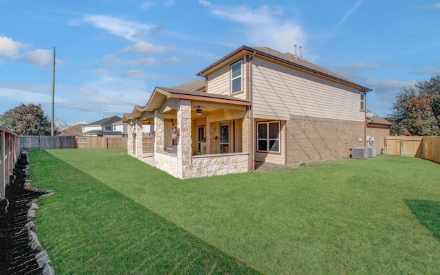 rear view of house featuring ceiling fan, central air condition unit, and a lawn