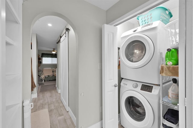 washroom with ceiling fan, stacked washing maching and dryer, and light wood-type flooring