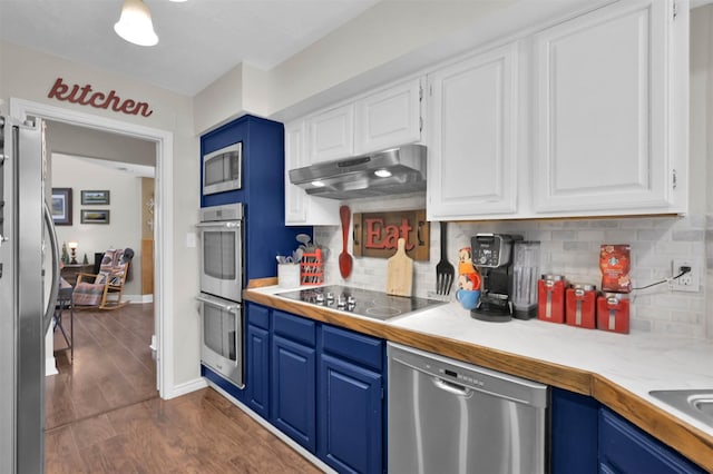 kitchen featuring dark wood-type flooring, blue cabinets, appliances with stainless steel finishes, decorative backsplash, and white cabinets