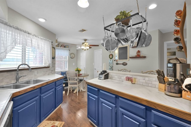 kitchen with dark hardwood / wood-style floors, black dishwasher, sink, backsplash, and blue cabinetry