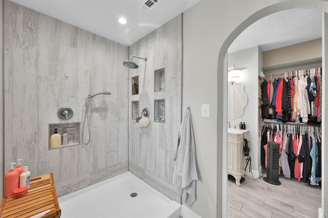 bathroom with vanity, tiled shower, and hardwood / wood-style floors