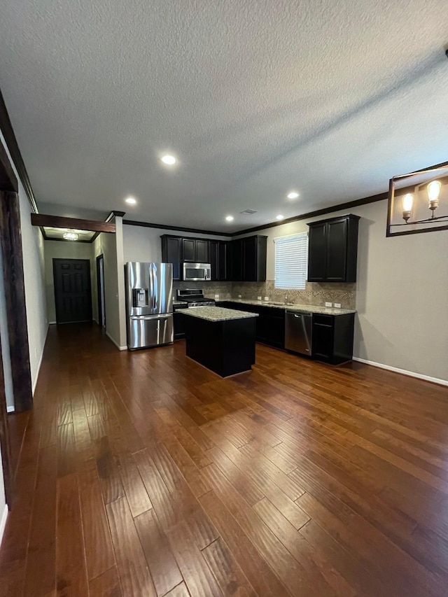 kitchen featuring appliances with stainless steel finishes, a center island, tasteful backsplash, ornamental molding, and dark hardwood / wood-style flooring