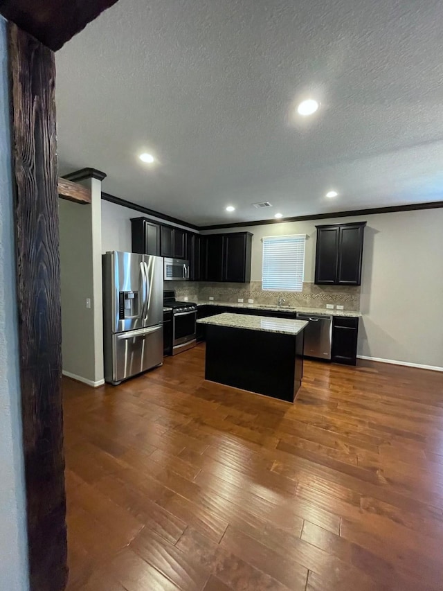 kitchen featuring appliances with stainless steel finishes, a center island, backsplash, and dark hardwood / wood-style floors