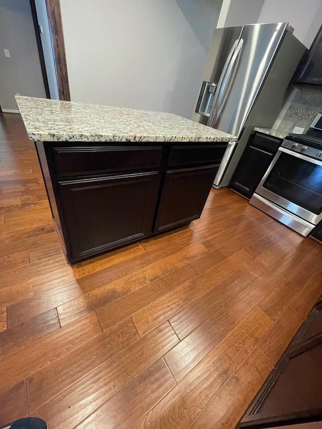 kitchen with light stone countertops, appliances with stainless steel finishes, and dark wood-type flooring