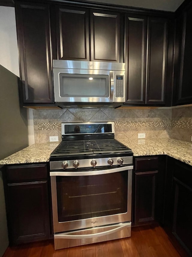 kitchen featuring light stone counters, appliances with stainless steel finishes, dark hardwood / wood-style floors, and backsplash