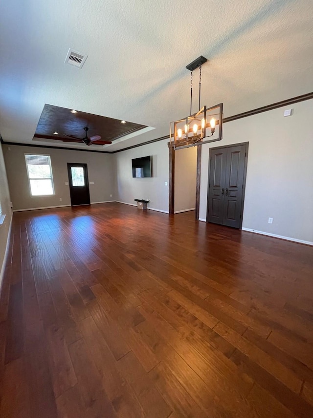 unfurnished room featuring crown molding, a textured ceiling, dark hardwood / wood-style floors, a raised ceiling, and ceiling fan with notable chandelier