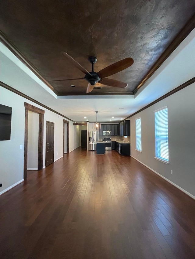 unfurnished living room featuring crown molding, a raised ceiling, and dark wood-type flooring