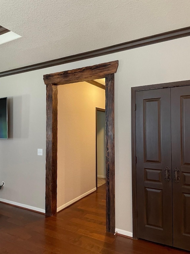 corridor featuring ornamental molding, dark hardwood / wood-style floors, and a textured ceiling