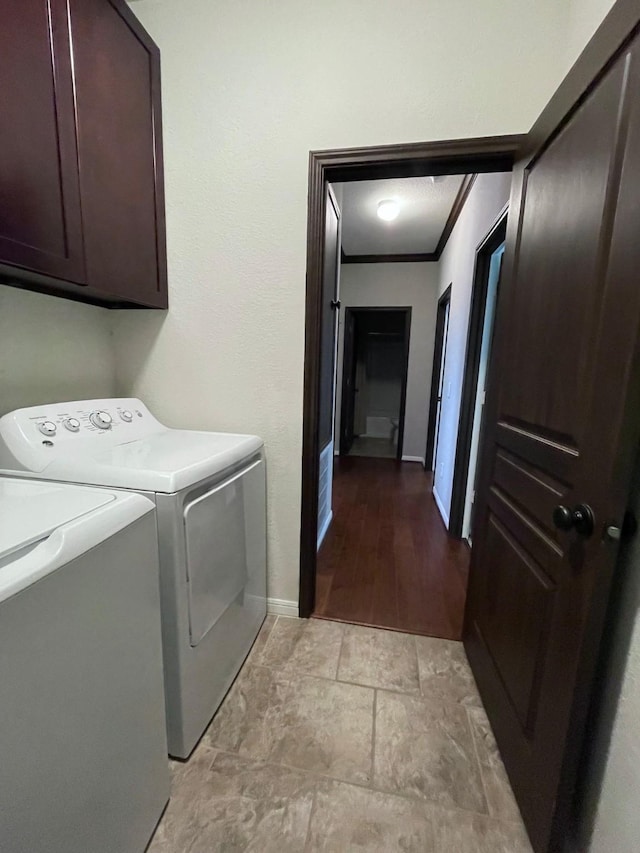 washroom with cabinets, ornamental molding, and washing machine and clothes dryer