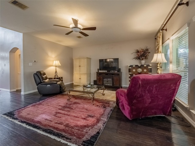 living area featuring visible vents, a ceiling fan, wood finished floors, arched walkways, and baseboards