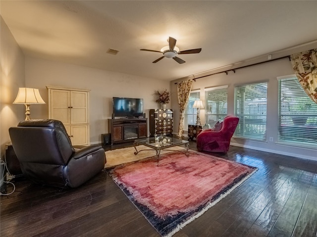 living area featuring hardwood / wood-style floors, visible vents, baseboards, and ceiling fan