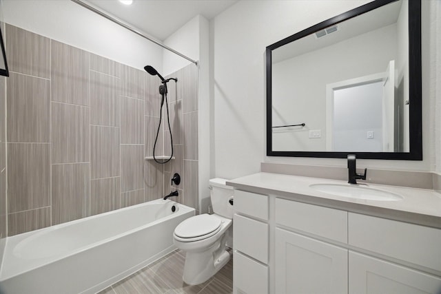 full bathroom featuring tiled shower / bath, vanity, and toilet