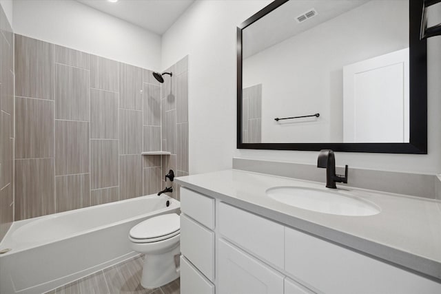 full bathroom with tiled shower / bath, vanity, and toilet