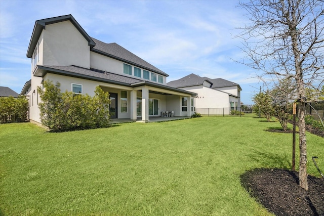 rear view of house featuring a lawn and a patio