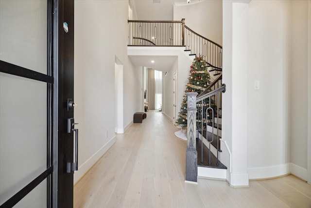 entryway with a towering ceiling and light hardwood / wood-style flooring