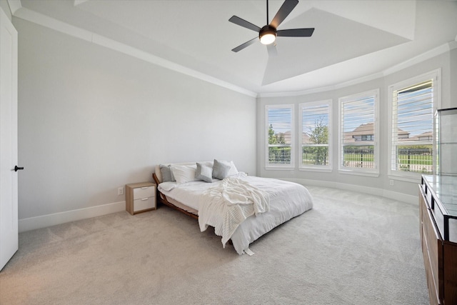 bedroom featuring ceiling fan, ornamental molding, a tray ceiling, and light carpet