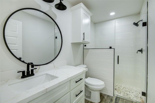 bathroom with a shower with door, vanity, hardwood / wood-style floors, and toilet