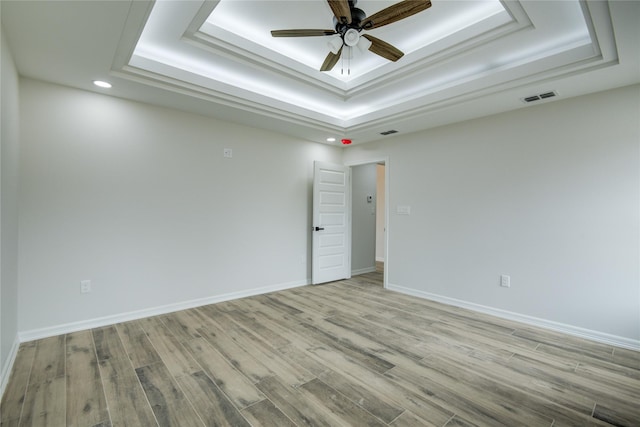 spare room featuring ceiling fan, a raised ceiling, and light hardwood / wood-style flooring