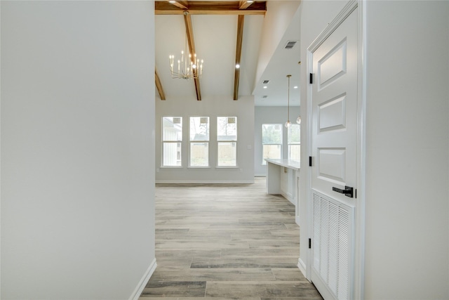 corridor featuring beamed ceiling, a notable chandelier, and light hardwood / wood-style floors