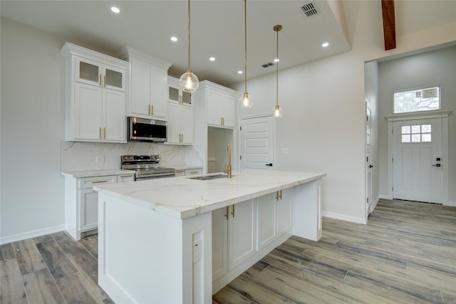 kitchen featuring pendant lighting, white cabinetry, stainless steel appliances, and an island with sink