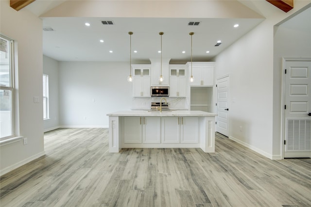 kitchen with sink, decorative light fixtures, an island with sink, stainless steel appliances, and white cabinets