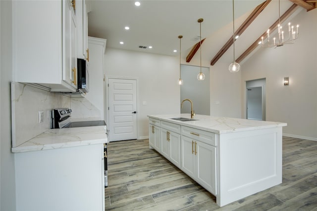 kitchen featuring pendant lighting, white cabinetry, light stone countertops, and a center island with sink