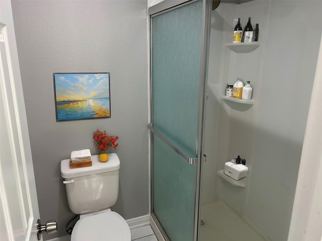 bathroom featuring toilet and a shower with door