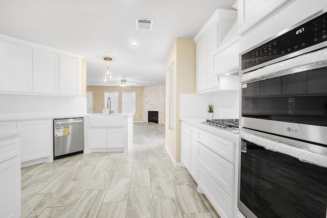 kitchen with ceiling fan, decorative light fixtures, stainless steel appliances, and white cabinets