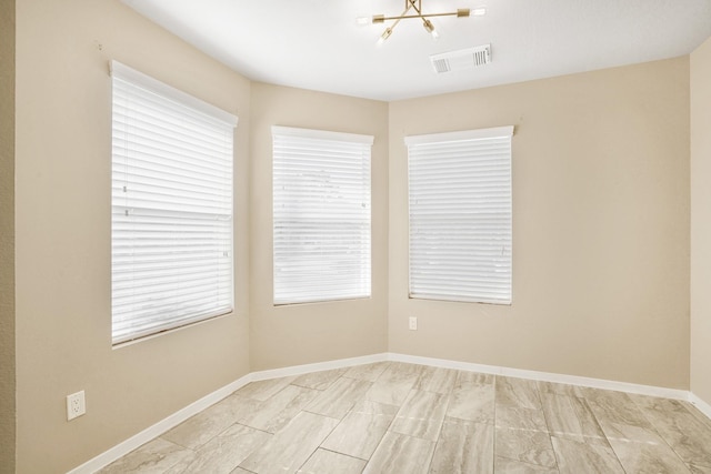 empty room featuring plenty of natural light and a chandelier